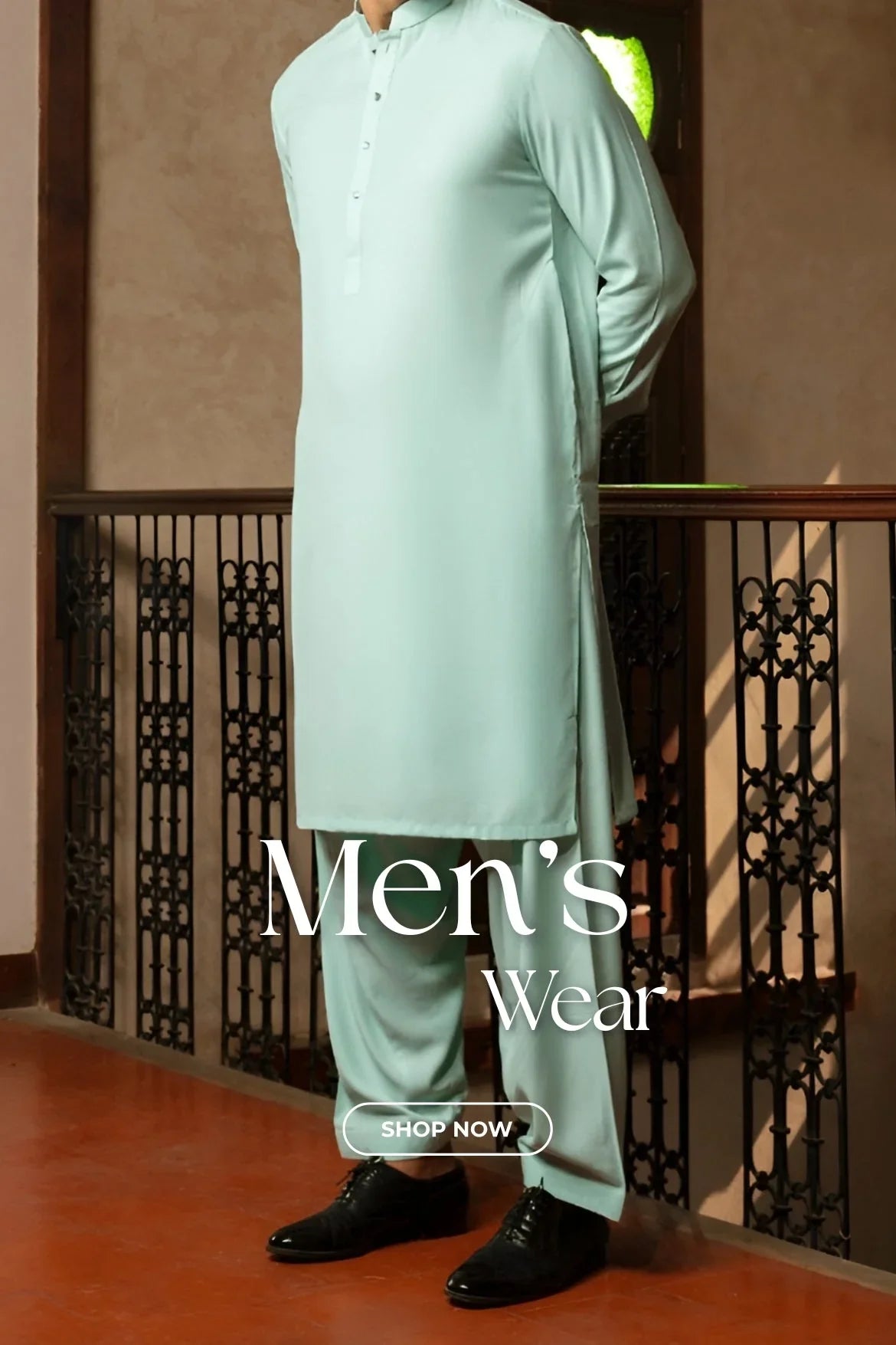 Man wearing light blue traditional men's kurta pajama with black dress shoes standing indoors