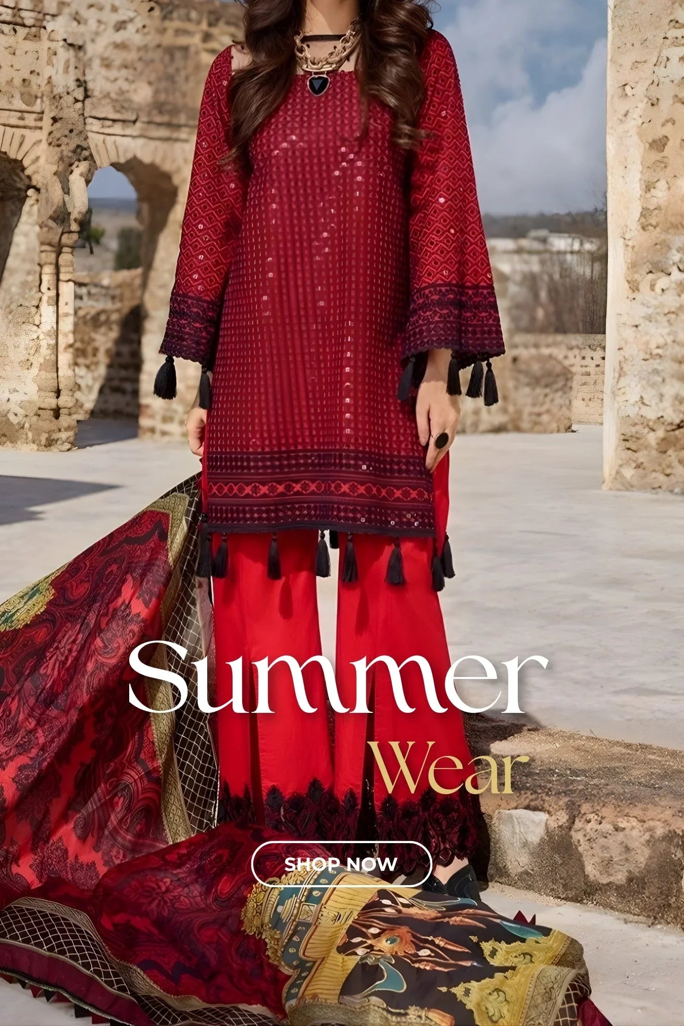 Woman wearing red embroidered summer wear with tassels and matching dupatta in outdoor ancient stone setting