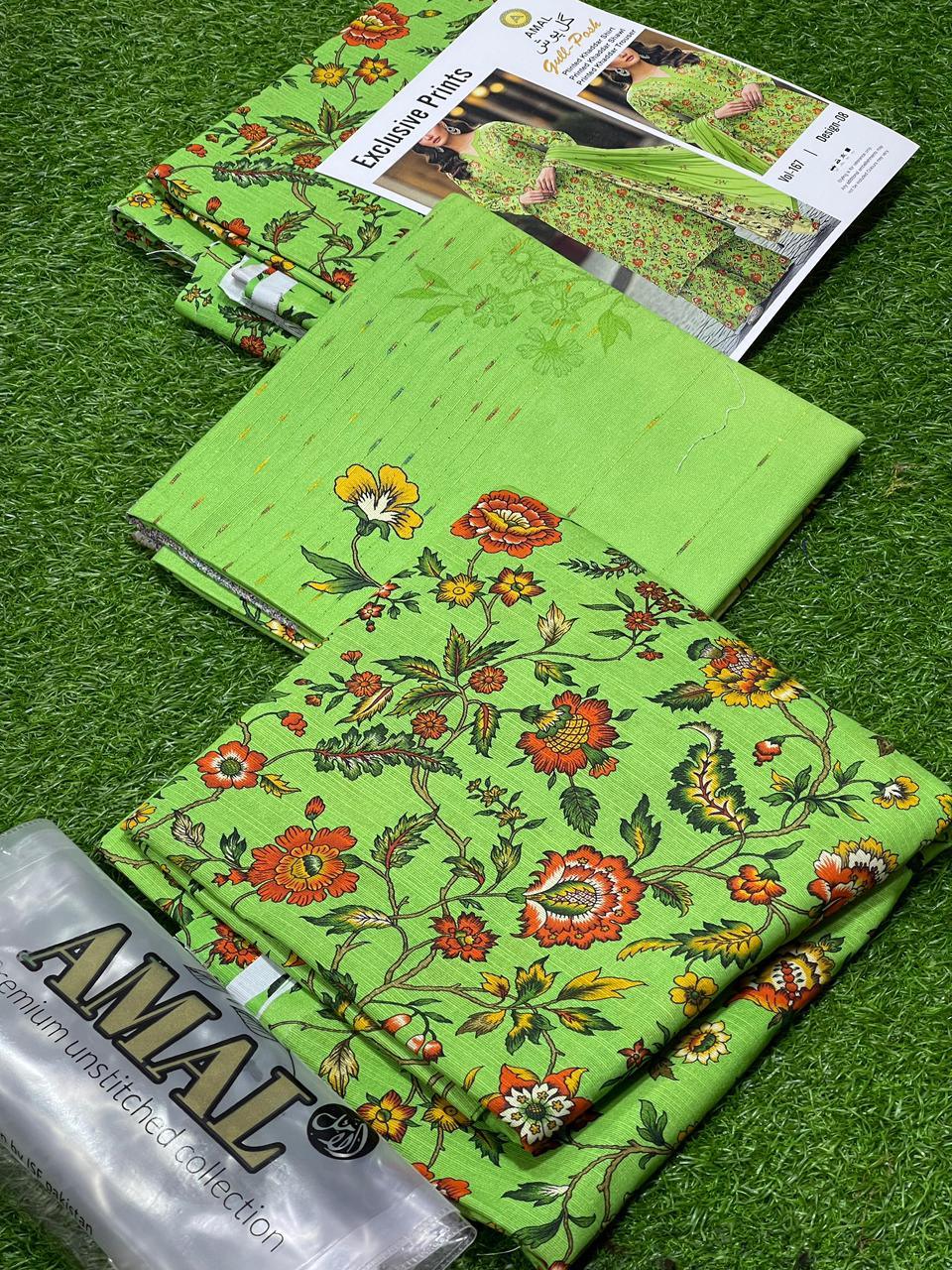 Green floral printed unstitched fabric set from AMAL premium collection with catalog on grass background