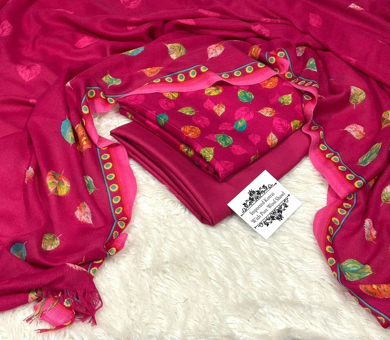 Bright pink pure wool shawl with vibrant leaf prints and intricate border, displayed on white fur