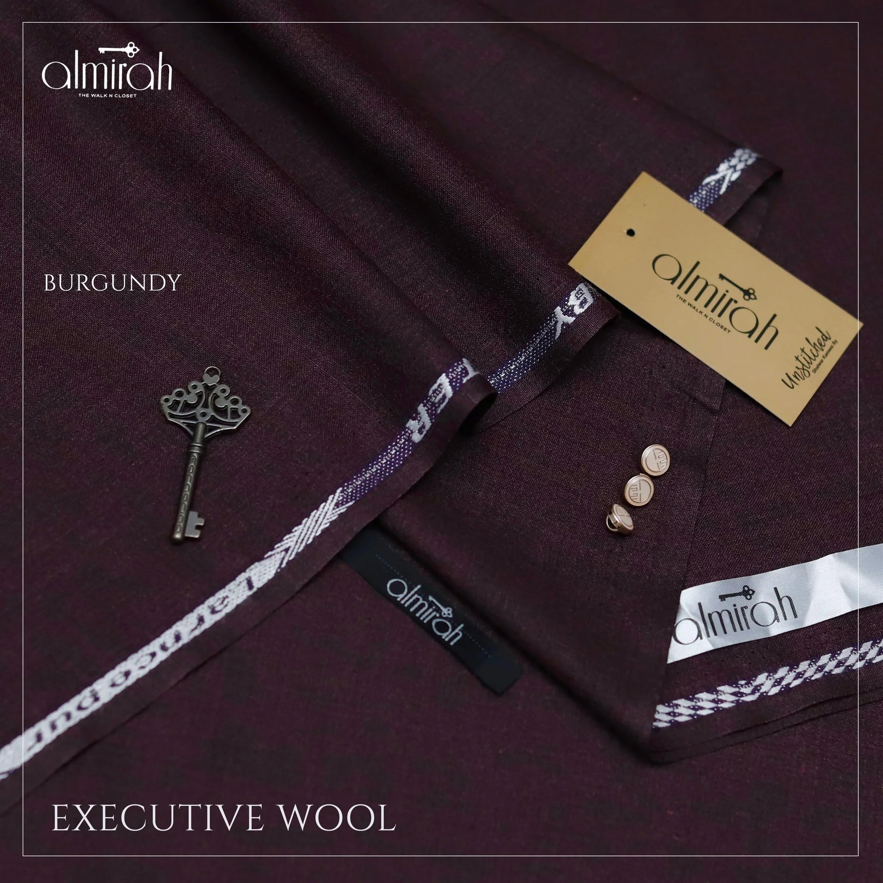 Burgundy executive wool fabric by Almirah with branded labels, buttons, and vintage key on fabric